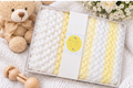Yellow and white crochet baby blanket presented in a gift box